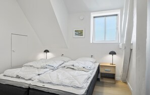 A bedroom with a bed, two bedside tables, a nightstand, a window, and a ceiling light.