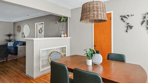A dining area with a wooden table, green chairs, a wicker pendant light, and wall art. - South Park Quiet 2bd Close to Downtown + AC (San Diego)
