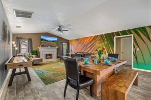 Ein geräumiges Wohnzimmer mit Billardtisch, Kamin und Essbereich mit Holztisch und Stühlen.