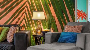 Una sala de estar moderna con un sofá, sillones y una mesita de noche con una lámpara.