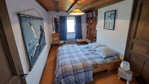Un dormitorio con cama, una estantería, un escritorio y una ventana con cortinas.