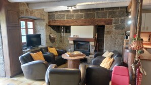 Un salón acogedor con paredes de piedra, sofás de cuero, una chimenea y un televisor.