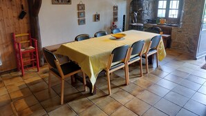 Comedor con una mesa larga cubierta por un mantel amarillo, rodeado de sillas.