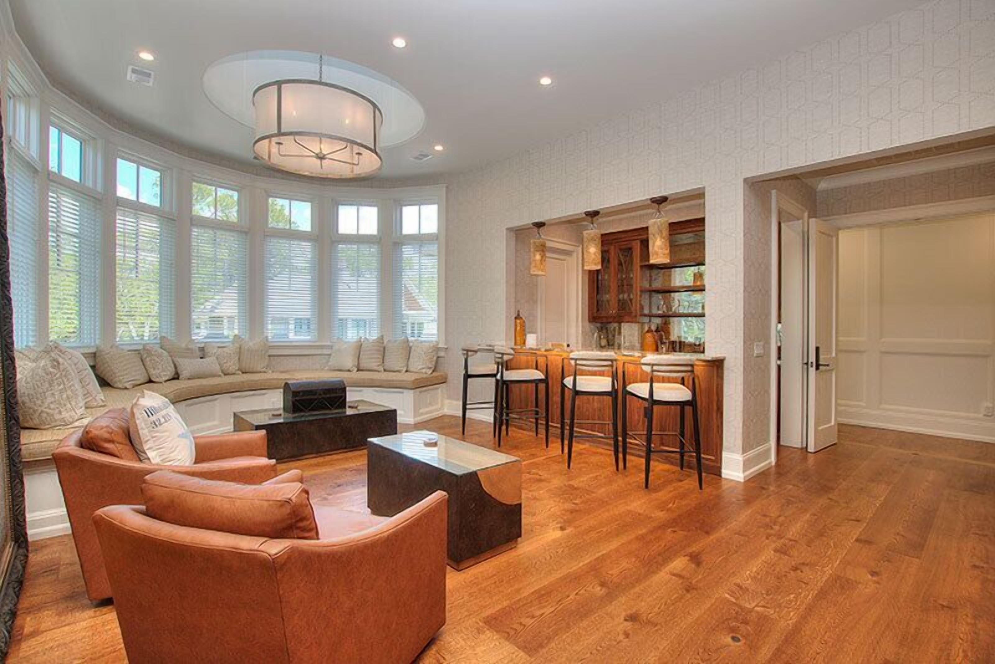 A spacious living room with a curved sofa, a coffee table, and a dining area with bar stools.