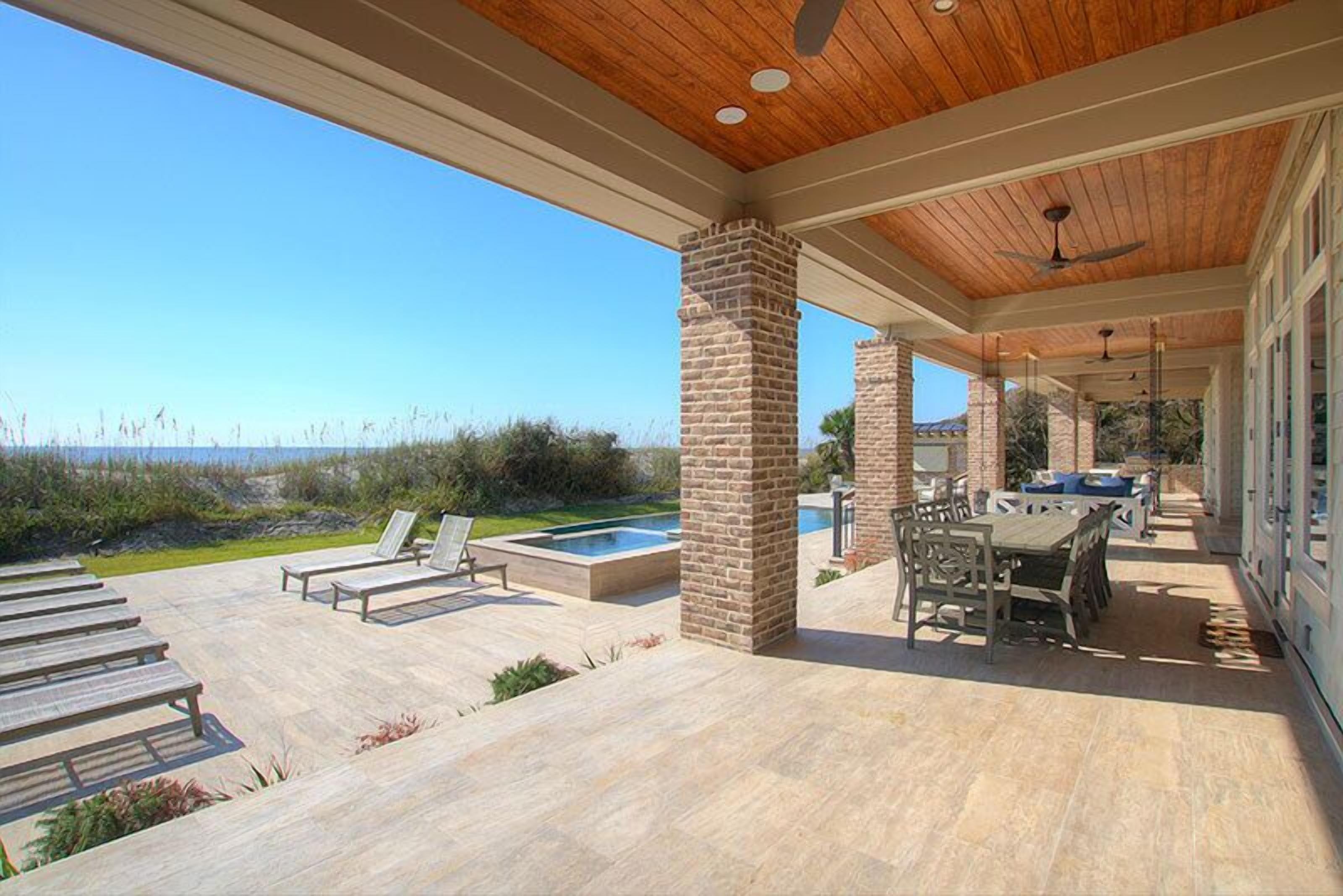 A covered outdoor patio with a pool, lounge chairs, and a dining area.