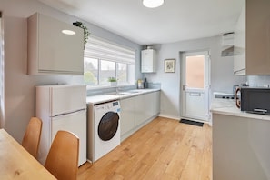 A modern kitchen with white cabinetry, a built-in washing machine, and a microwave. - Host & Stay | Bartlemere House (Barnard Castle)