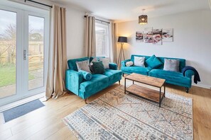 A living room with a teal sofa set, a wooden coffee table, and a patterned rug.