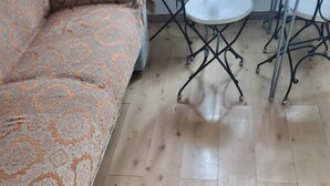 Une pièce avec un canapé orange à motifs, une petite table ronde et un plancher en bois.
