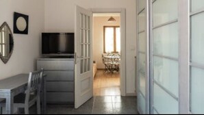 Une pièce comprenant une table à manger et des chaises, un téléviseur et une armoire dont les portes sont en verre dépoli.