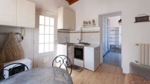 Une cuisine compacte avec des meubles blancs, une cuisinière et un petit coin repas comprenant une table et des chaises.