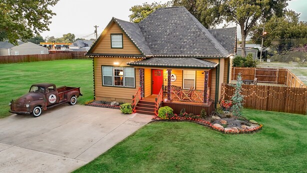 Une maison de plain-pied avec une porte rouge, un porche à l’avant et un petit jardin.