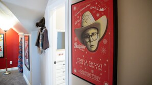 Un couloir avec une affiche encadrée au mur, un porte-manteau et une porte.