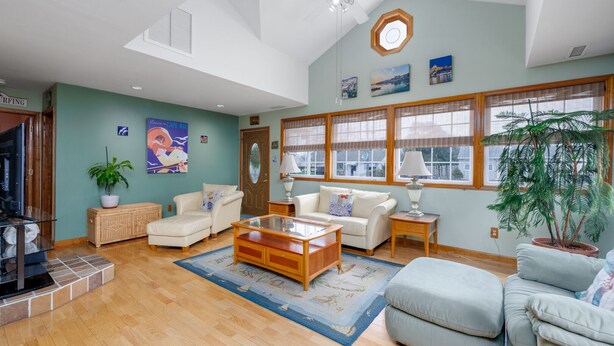 A spacious living room with a high ceiling, large windows, and a variety of seating options including a sofa, armchairs, and a coffee table.