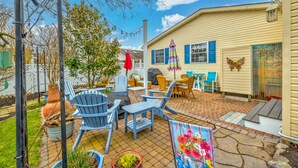 A backyard patio with outdoor furniture, a dining table, and a colorful painting.