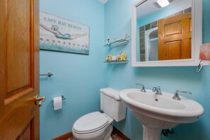 Ein Badezimmer mit Toilette, Waschbecken und einer Holztür.