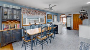 A kitchen with a dining table, chairs, a built-in oven, and a window with curtains.