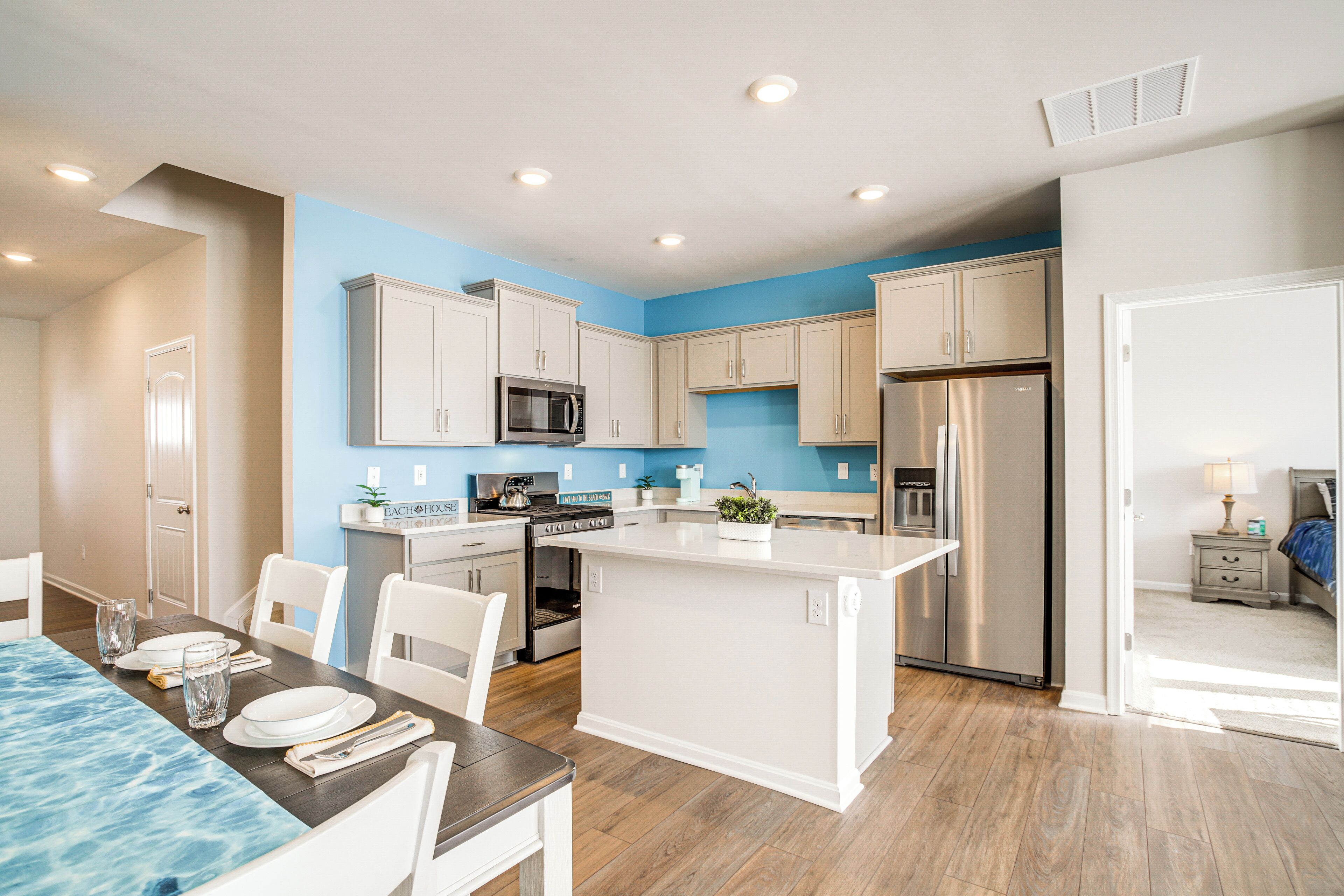 A modern kitchen with white cabinets, stainless steel appliances, and a central island.