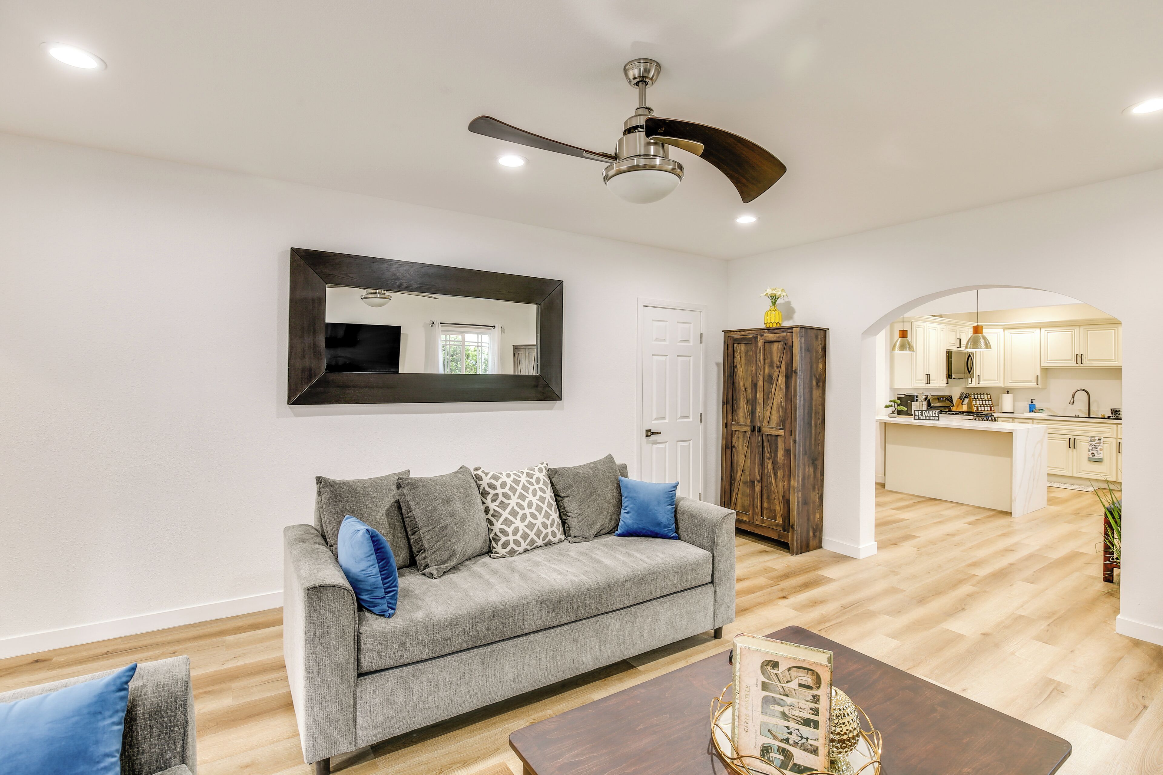 A living room with a grey sofa, a wooden coffee table, and a ceiling fan.