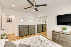 Quarto com cama, cômoda e televisão na parede.