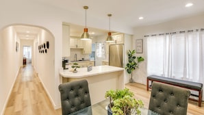 A modern kitchen with white cabinets, a stainless steel refrigerator, and pendant lighting.