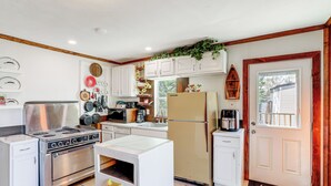A kitchen with white cabinets, a stainless steel stove, a refrigerator, and a coffee maker. - Arkansas Cabin w/ Deck < 1 Mi to Norfork Lake (Henderson)