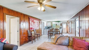 A spacious living area with a wooden interior, a ceiling fan, a dining table with chairs, and a kitchen in the background. - Arkansas Cabin w/ Deck < 1 Mi to Norfork Lake (Henderson)