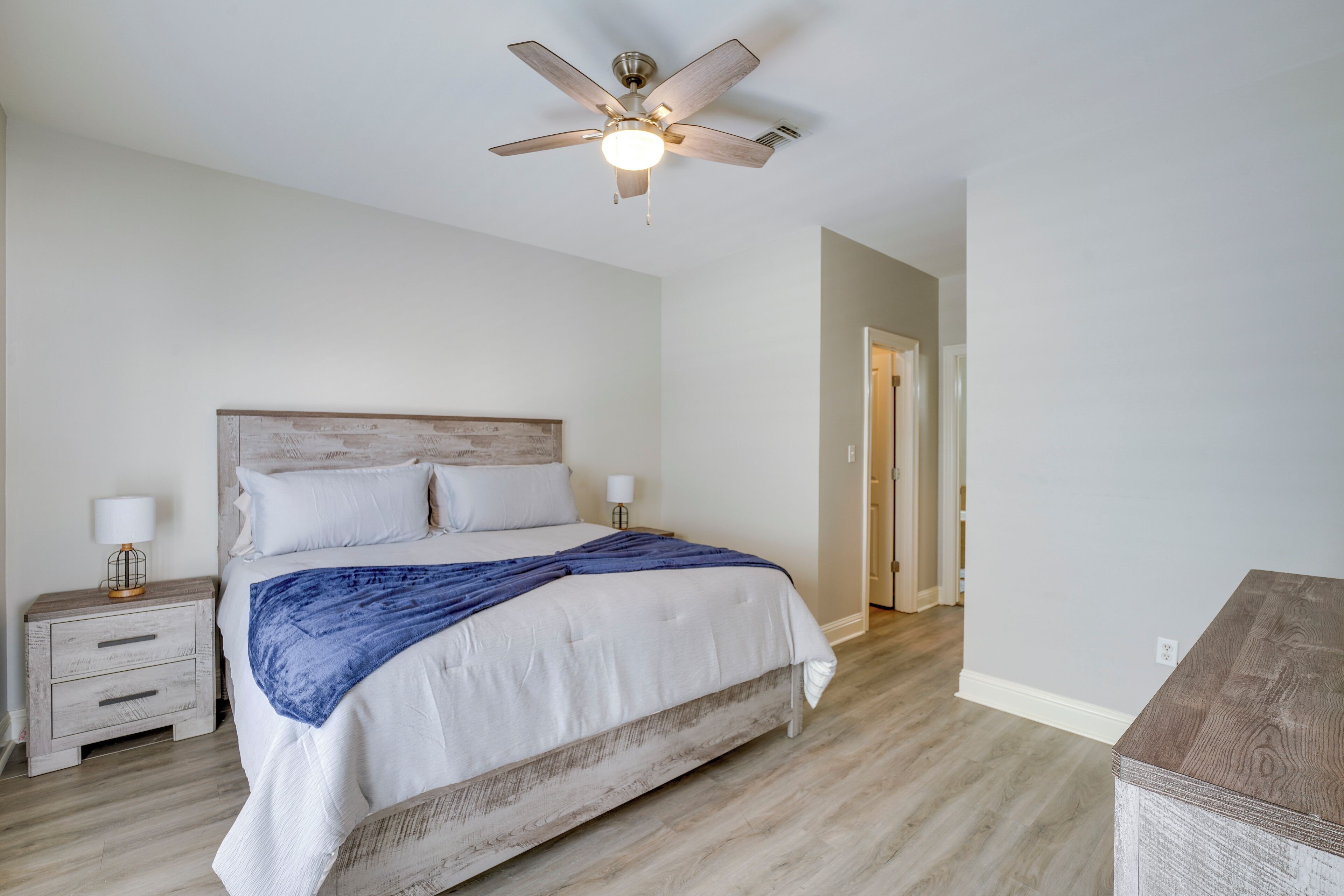A bedroom with a bed, nightstands, a ceiling fan, and a wooden dresser.