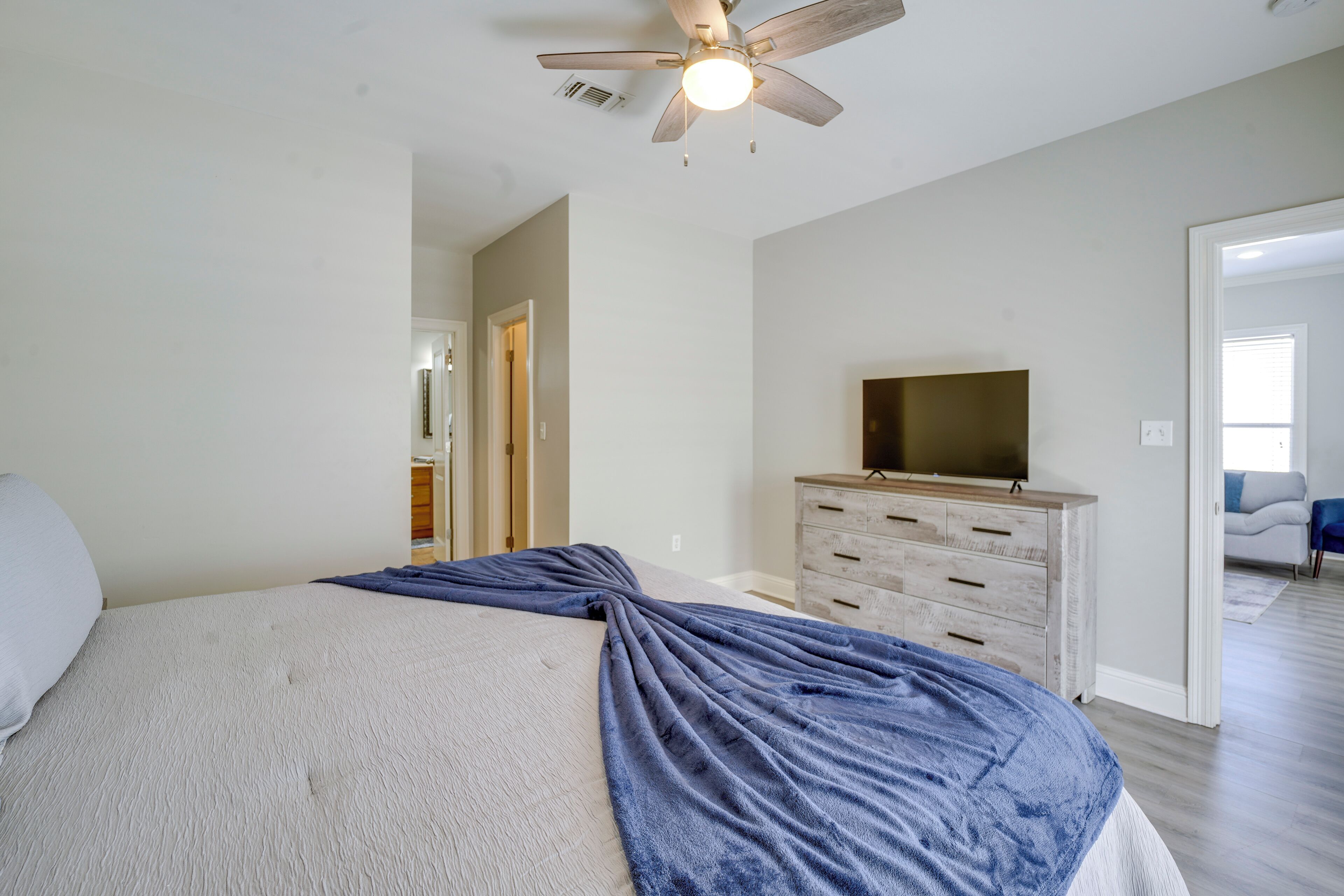 Ein Schlafzimmer mit einem Bett, einem Schminktisch, einem Fernseher und einem Deckenventilator.