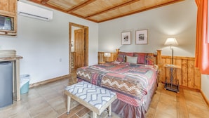 A bedroom with a wooden ceiling, a bed with a patterned bedspread, a bedside table, a lamp, and a small table with a lamp. - 5 Mi to Alto Lake! Pet-friendly Ruidoso Studio (Ruidoso)