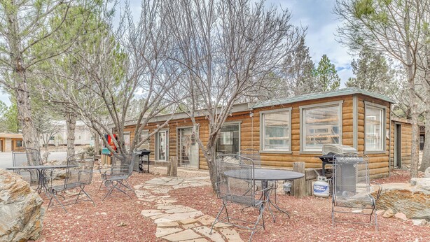 A log cabin with a stone pathway leading to metal chairs and tables, surrounded by trees. - 5 Mi to Alto Lake! Pet-friendly Ruidoso Studio (Ruidoso)