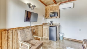 A compact kitchen with wooden cabinets, a built-in microwave, a small refrigerator, and a flat-screen TV mounted on the wall. - 5 Mi to Alto Lake! Pet-friendly Ruidoso Studio (Ruidoso)