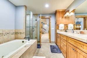 A modern bathroom with a large bathtub, wooden cabinets, and a glass shower enclosure.