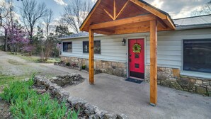 Une maison avec une porte rouge, des fondations en pierre et un porche en bois.