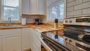 A modern kitchen with white cabinets, a wooden countertop, a stainless steel oven, and a coffee maker. - Cozy Henderson Studio - 2 Mi to Norfork Lake! (Henderson)