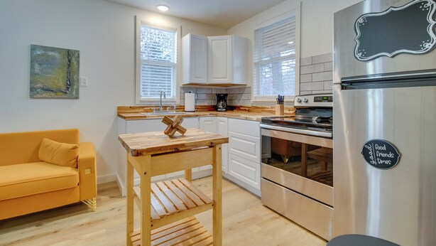 A modern kitchen with white cabinets, a stainless steel refrigerator, and a wooden table. - Cozy Henderson Studio - 2 Mi to Norfork Lake! (Henderson)