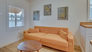 A modern living room with a sofa, a coffee table, and abstract wall art. - Cozy Henderson Studio - 2 Mi to Norfork Lake! (Henderson)