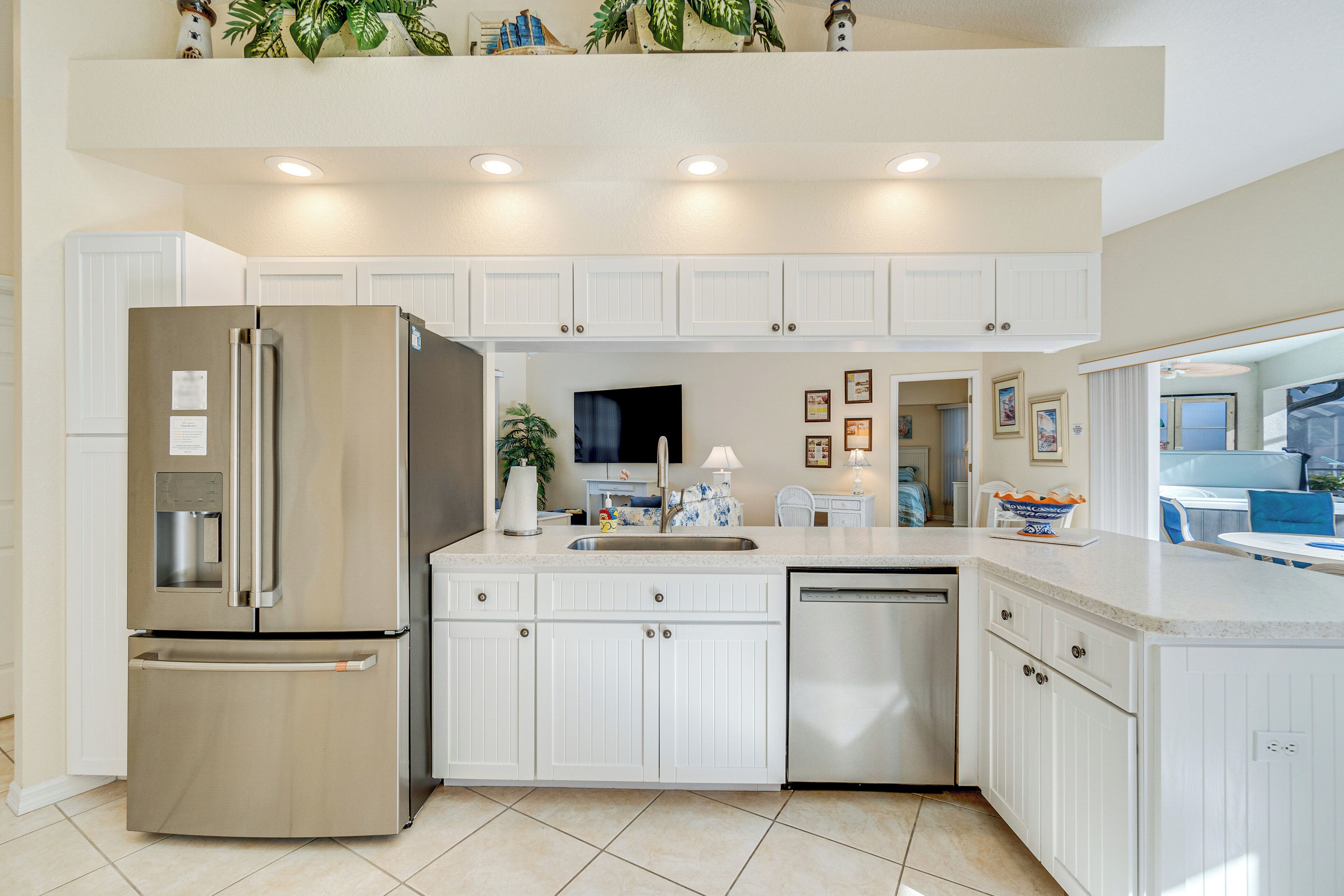 A modern kitchen with white cabinetry, stainless steel appliances, and a built-in dishwasher.