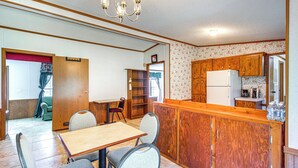 A compact kitchen with wooden cabinets, a central island, and a dining area with chairs. - 'valley View Lodge' Rural Home in Bridgeport! (Bridgeport)