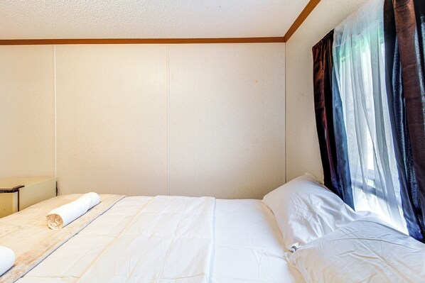A hotel room with a neatly made bed, a small bedside table, and a window with sheer curtains. - 'valley View Lodge' Rural Home in Bridgeport! (Bridgeport)