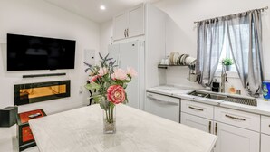 A modern kitchen with white cabinets, a built-in oven, and a large window with curtains.