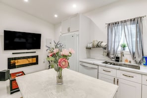 Uma cozinha moderna com armários brancos, forno embutido e uma janela grande com cortinas.