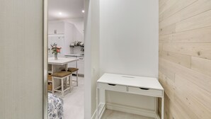 A modern, minimalist room with a white desk, a small stool, and a patterned rug.
