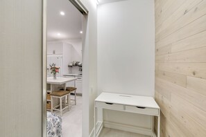 Quarto moderno e minimalista com uma escrivaninha branca, um banquinho pequeno e um tapete estampado.