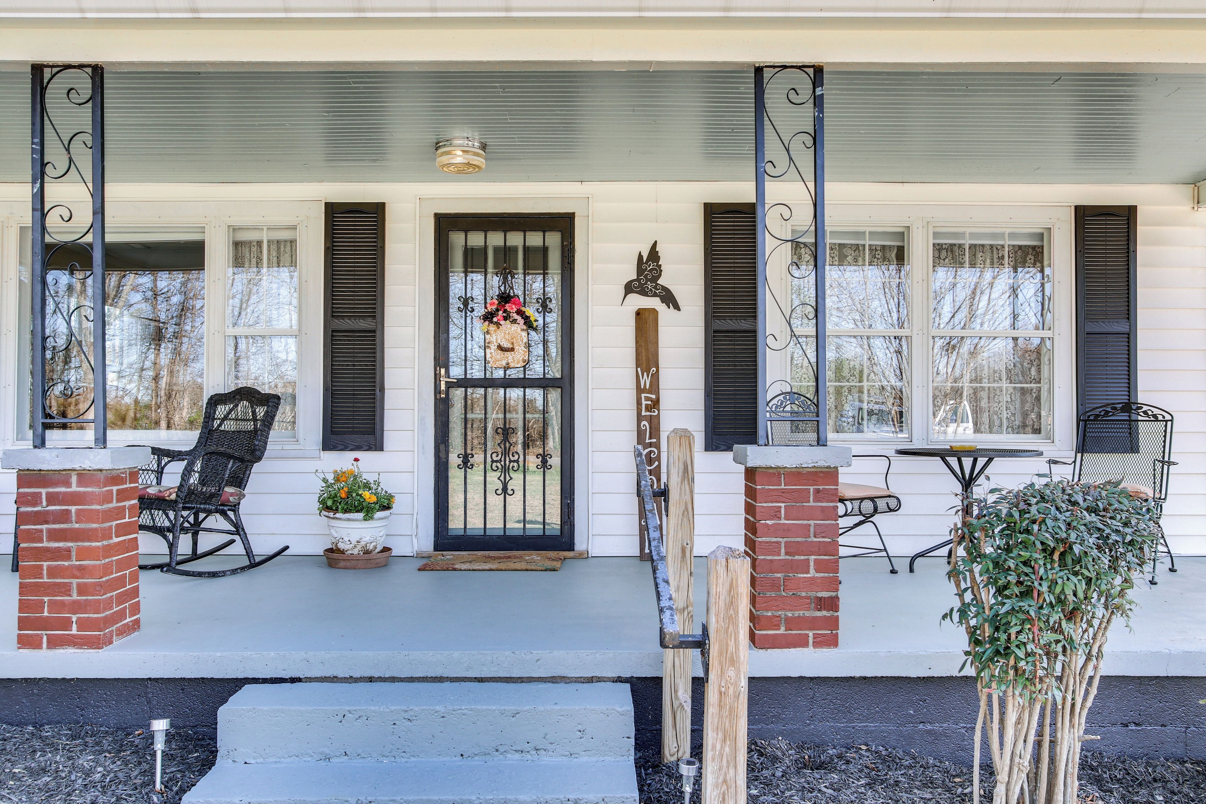 A porch with a rocking chair, a potted plant, and a wooden sign with 'WELCOME' written on it.