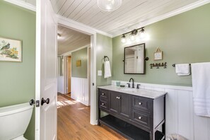 A bathroom with a white toilet, dark wooden vanity, and a green wall.