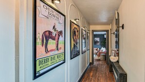Un couloir orné de reproductions d’affiches historiques encadrées, doté d’un plancher en bois et d’un banc surmonté d’un lavabo blanc.