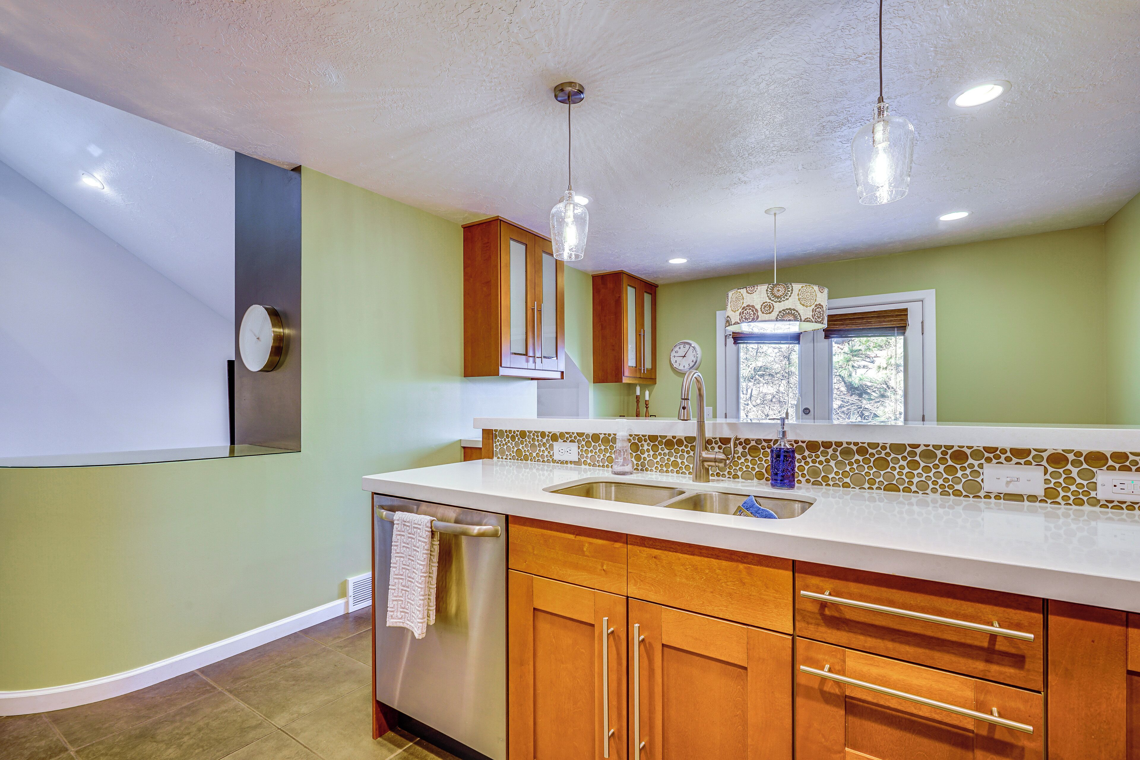A kitchen with wooden cabinets, a stainless steel dishwasher, and a white countertop.