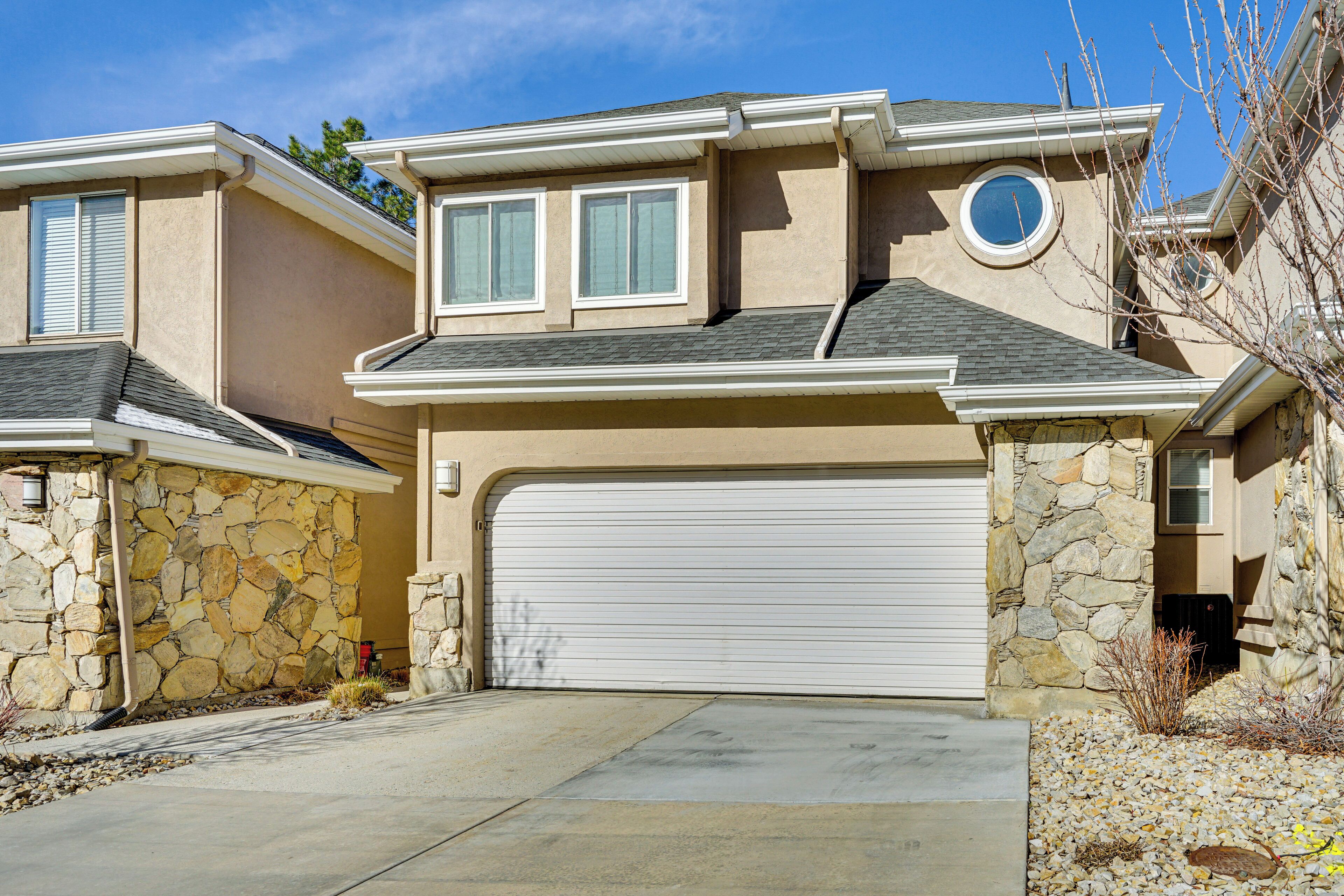 A two-story house with a stone facade, a garage, and a small circular window.