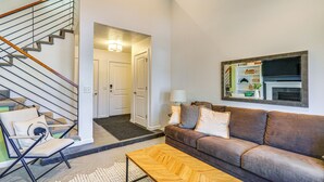 A modern living room with a brown leather sofa, a wooden coffee table, and a black metal staircase. - Modern Townhome w/ Hot Tub: 10 Mi to Snowbird! (Salt Lake City)