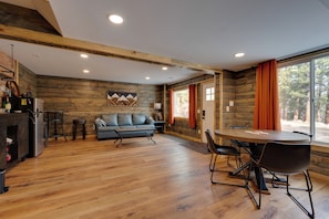 Uma sala de estar moderna com piso de madeira, um sofá, uma mesa de jantar com cadeiras e uma lareira.